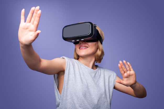 Lachende vrouw vertrouwen dragen VR-headset-apparaat lucht aanraken tijdens virtual reality-ervaring geïsoleerd op paarse achtergrond Digitale technologie entertainment Video game