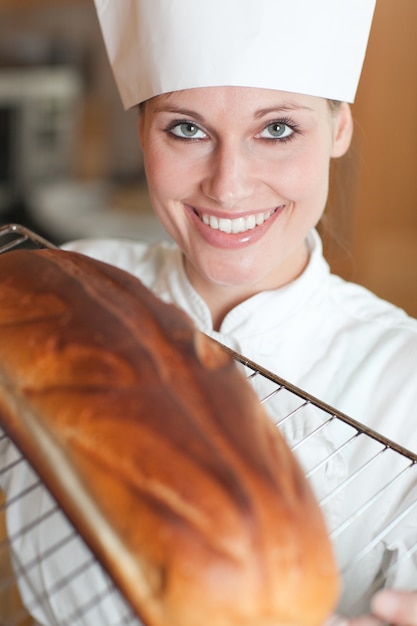 Lachende vrouwelijke chef-kok brood bakken