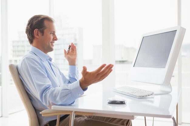 Lachende zakenman achter zijn bureau op video-chat