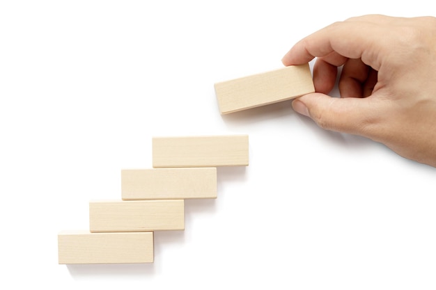 ビジネスの成長の成功プロセスの概念のためのはしごのキャリアパス白い背景の上の階段として木製のブロックの積み重ねを手で配置