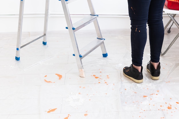 Ladder with paint in bucket near color wall indoors. Renovation and redecoration.