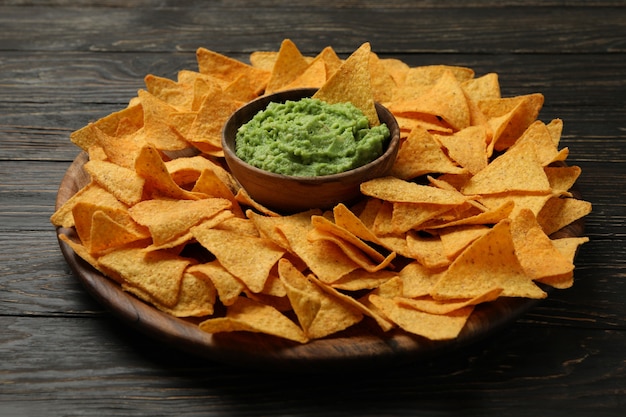 Lade met chips en kom guacamole op houten achtergrond, close-up