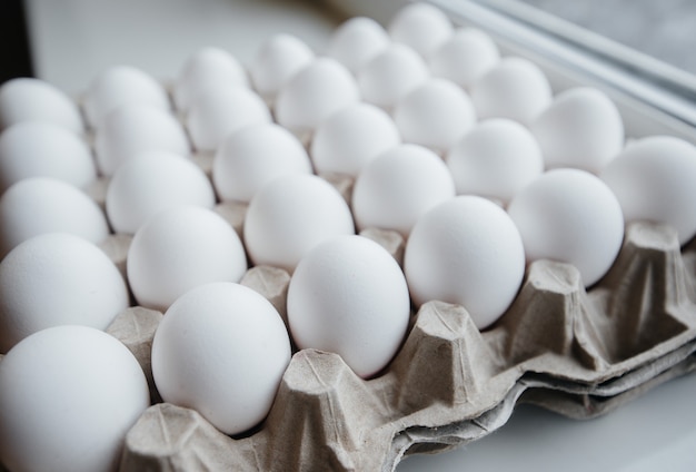 Lade van witte verse eieren close-up op een kartonnen vorm. Agrarische industrie