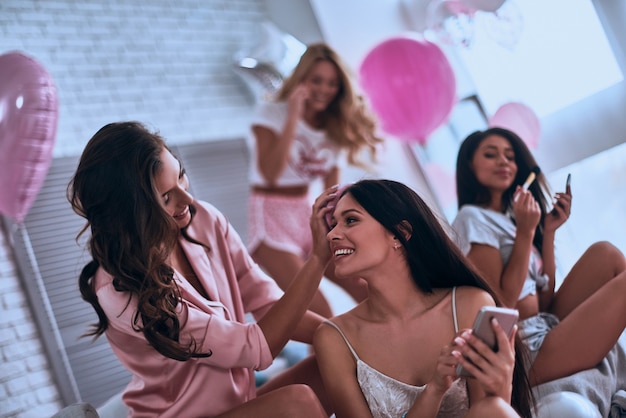 Ladies things to do. Attractive young women in pajamas smiling during beauty treatment while sitting in the bedroom