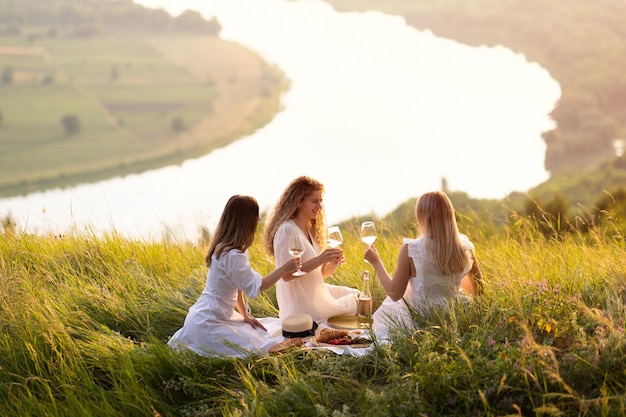 写真 ワインを手にしている女性はピクニックで時間を過ごすことを楽しんでいます
