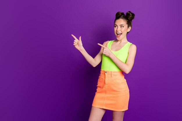 Lady directing fingers side empty space wear green singlet denim jeans skirt isolated violet color background