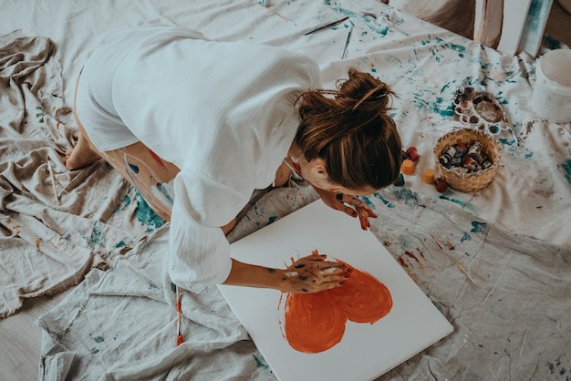 Lady draw a watercolor heart on white canvas