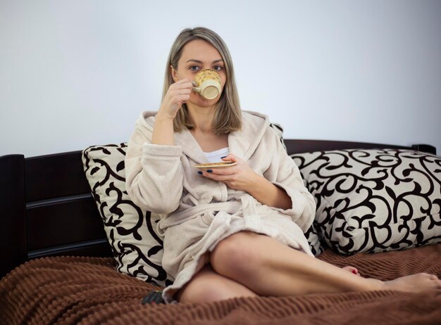 Foto alla signora piace bere caffè o tè seduta sul divano a casa