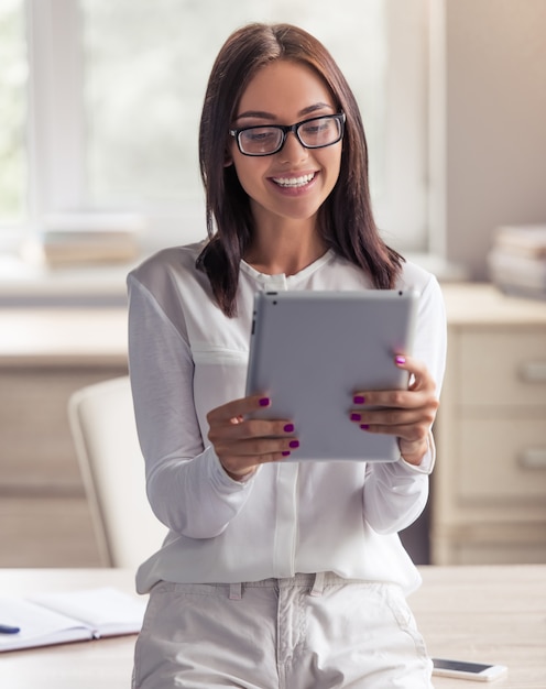 Lady in eyeglasses is using a digital tablet.