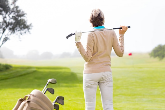 Photo lady golfer holding her club behind her head