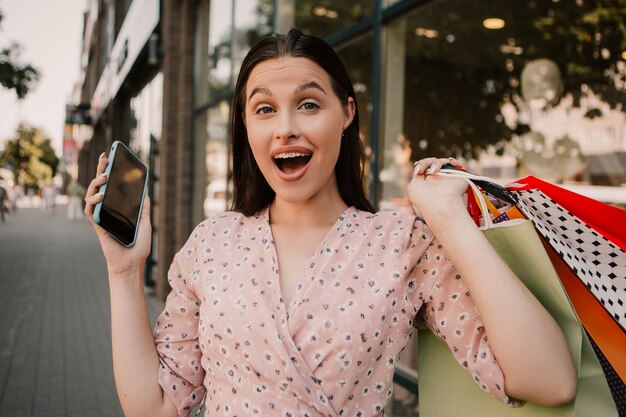 女性は買い物の後にたくさんのバッグと電話を持っています