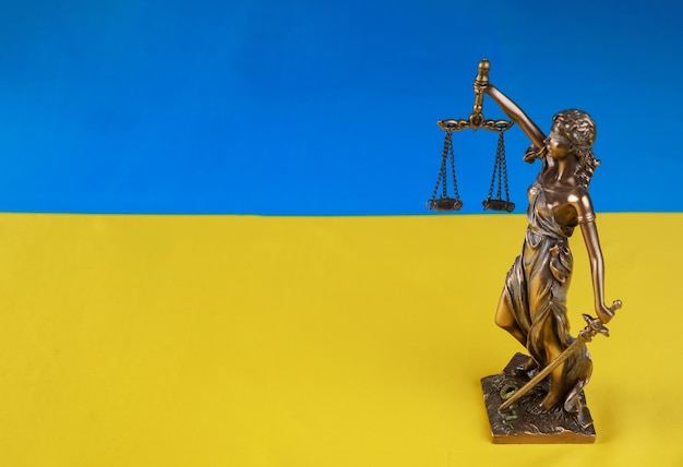 Lady Justice holding the scales on flag of Ukraine background Russian terrorist attack