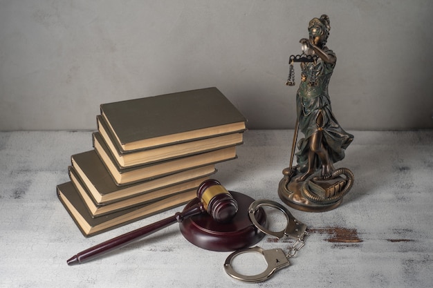 Lady Justice, Judge's gavel, books, handcuffs on an old wooden table