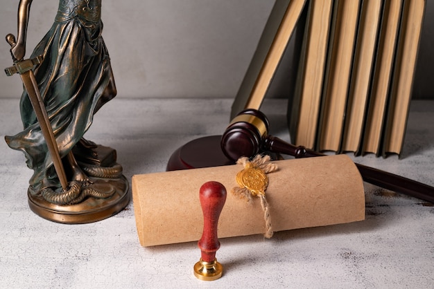 Lady justice, judge\'s gavel, books, parchment scroll with seal\
and stamp on an old wooden table