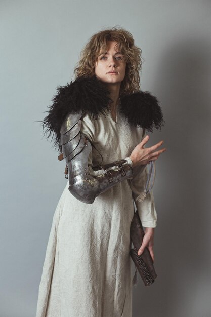 Lady knight with metal glove in antique clothes in studio\
portrait picture