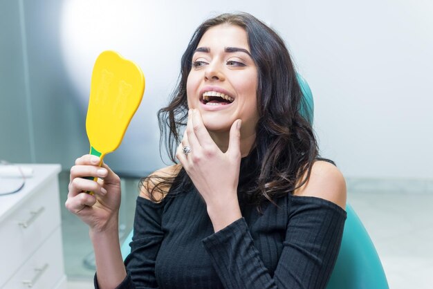 Lady looking at her teeth woman holding mirror dentist office