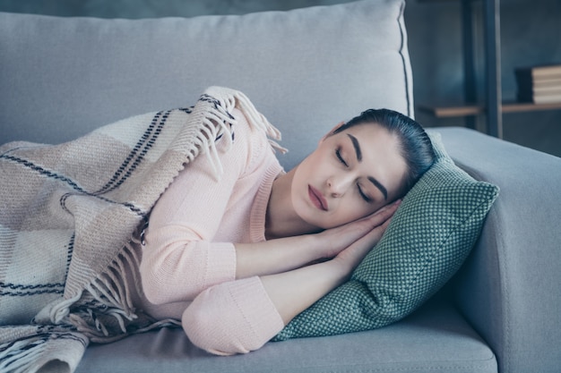 快適なソファの睡眠で覆われた毛布を横になっている女性