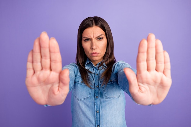 Lady making stop gesture with her palm on a blue background