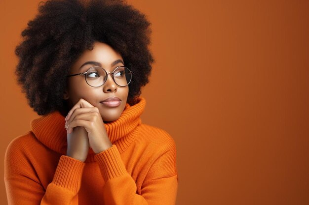 Lady in orange hoodie propping chin on finger and looking pensive