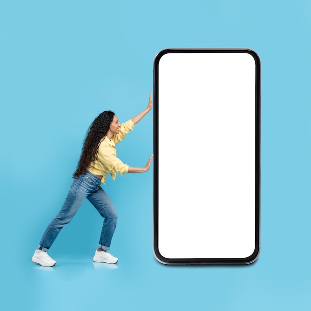 Lady posing with huge cellphone blank screen over blue background