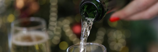 Lady pouring tasty champagne from bottle into glass to raise toast on celebration