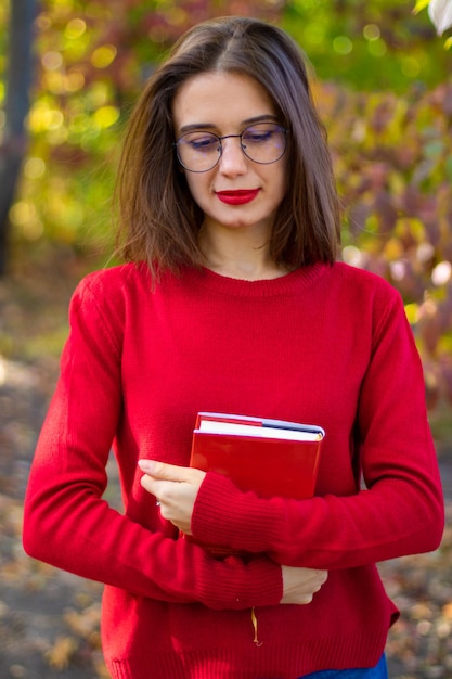 Lady in red sweater reads in nature. Girl and book