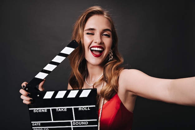 Lady in red top winking holding clapperboard and taking selfie