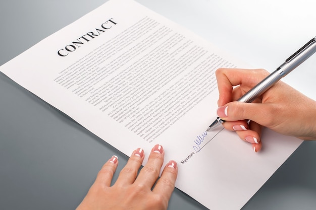 Lady's hand ondertekening promotiecontract. vrouwelijke hand ondertekent promotiecontract. wij zullen je helpen. bedrijven moeten elkaar helpen.