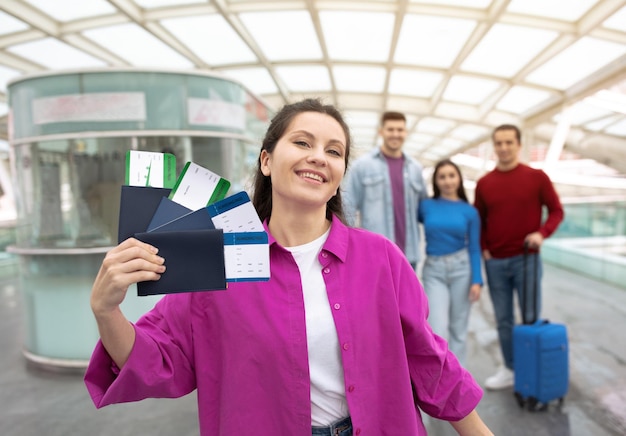 Lady showing boarding passes tickets posing with friends at airport
