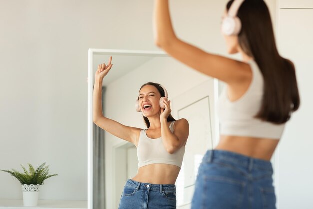 Photo lady singing favorite song wearing earphones listening music at home
