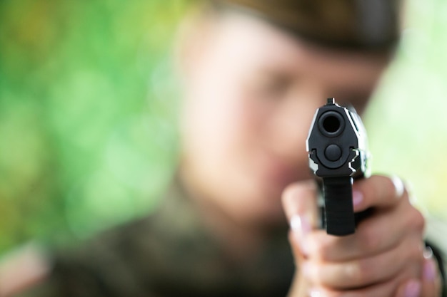 Photo the lady soldier aims straight at the camera with a short gun