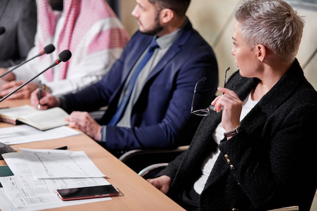 Lady in suit listening to political leader having discussion, sitting at desk in boardroom, coworking. meeting without ties, business concept