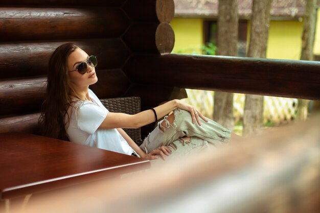 lady in sunglasses at the wooden house posing