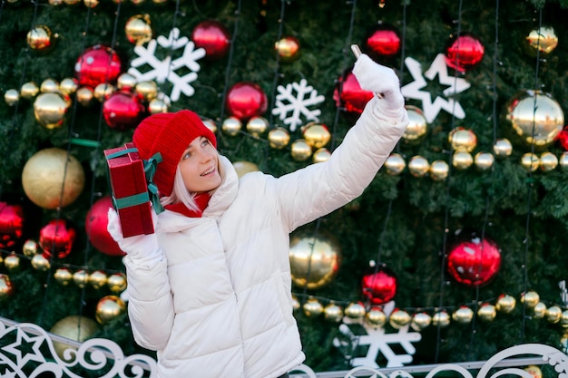 Lady takes selfie showing gift box looking into camera