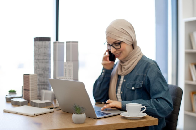 Lady talking on phone and using laptop at work