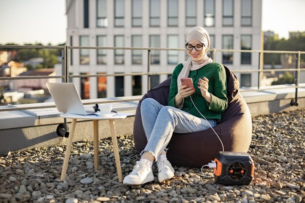 屋外でポータブル発電所に接続された電話を使用している女性