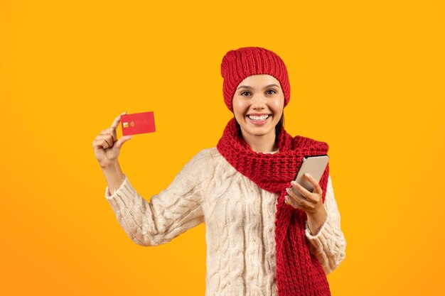 Фото Женщина использует приложение для покупок на смартфоне, держа в руках студию с кредитной картой