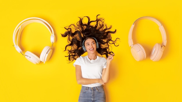 Lady wearing headphones pointing finger at earphones lying in studio