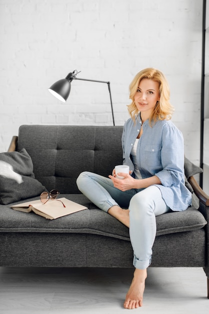 Lady with book and cup of coffee on black couch