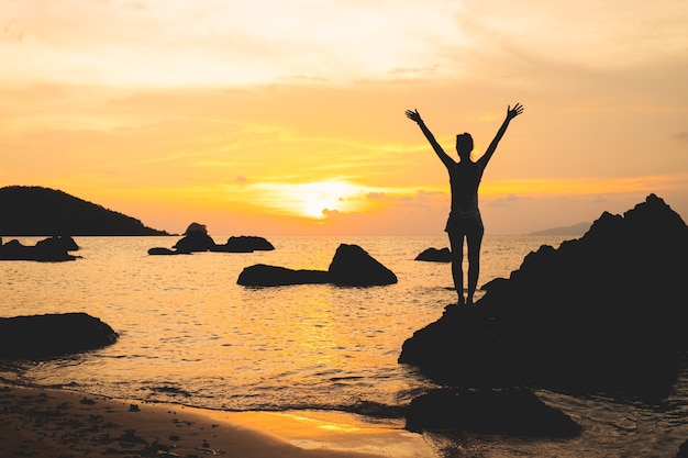 Ladys silhouette with raised arms against sunset