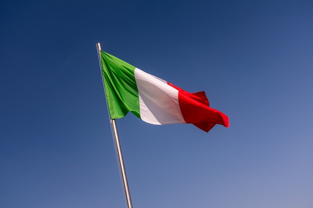 Lage hoek mening van Italië vlag zwaaien tegen de heldere blauwe hemel