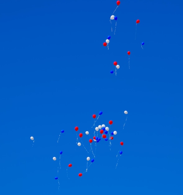 Lage hoek van ballonnen die tegen de blauwe hemel vliegen