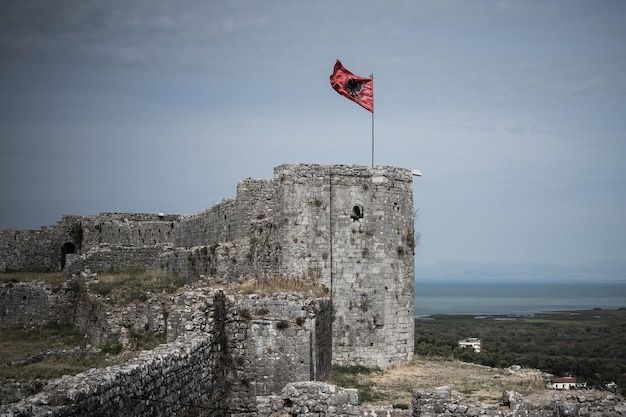 Lage hoek van de Albanese vlag op oude ruïnes tegen de lucht