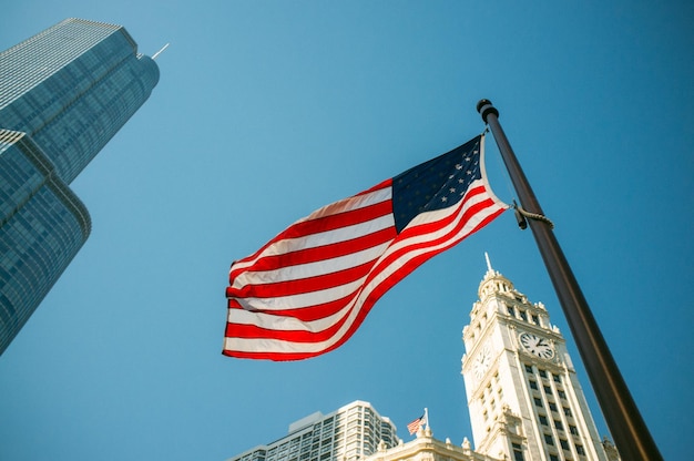 Lage hoek van de Amerikaanse vlag en stadsgebouwen tegen een heldere blauwe hemel
