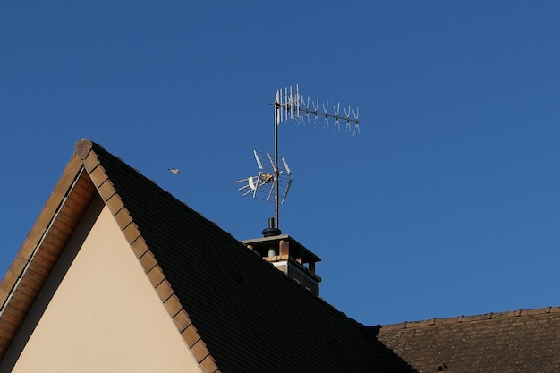 Lage hoek van de antenne op het dak van het huis tegen een heldere hemel