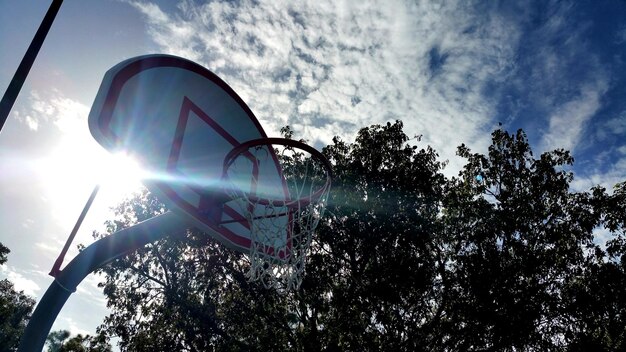 Foto lage hoek van de basketbalhoepel door silhouette bomen tegen de lucht