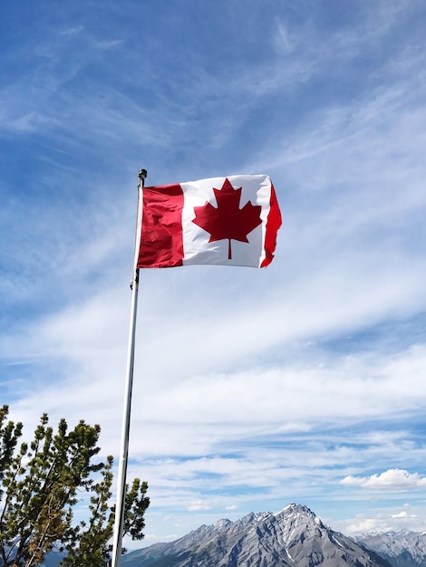 Lage hoek van de Canadese vlag die zwaait met de berg op de achtergrond tegen de lucht