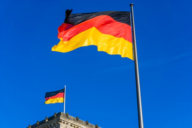 Foto lage hoek van de duitse vlag op het reichstag-gebouw tegen een heldere blauwe hemel tijdens een zonnige dag