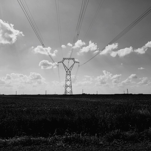 Foto lage hoek van de elektriciteitspylon op het veld tegen de lucht