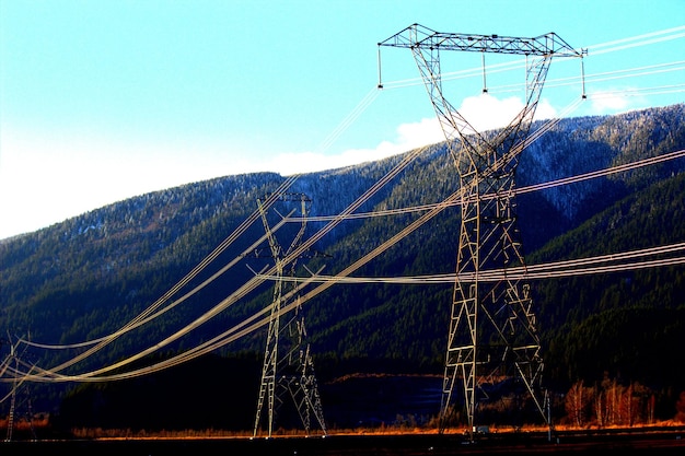 Foto lage hoek van de elektriciteitspylon tegen de berg